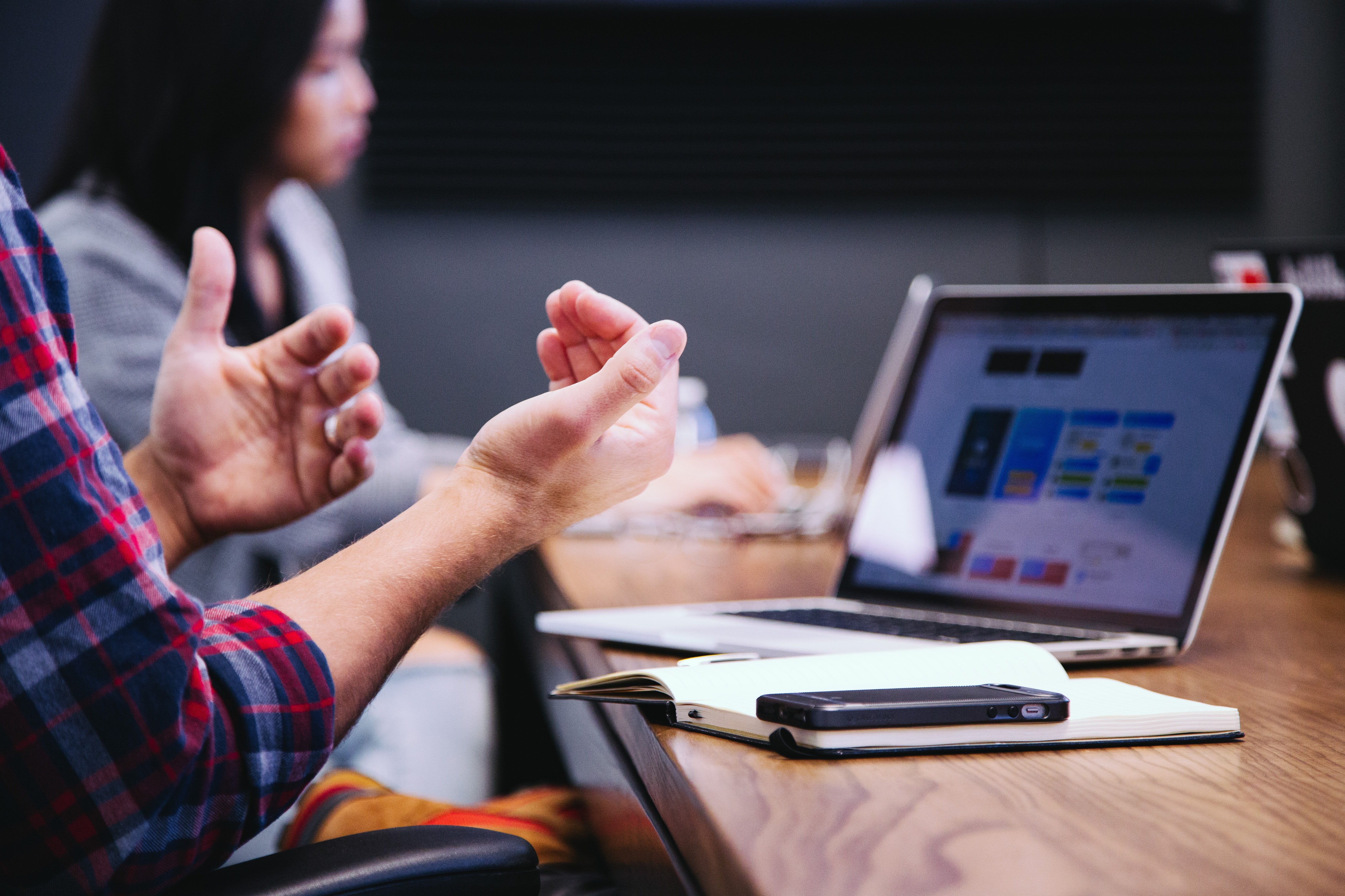 a computer sits on a desk next to a person's hands moving while they explain something